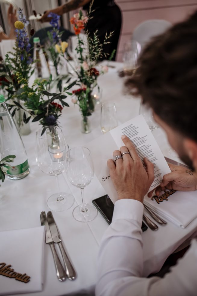 Bräutigam liest das Hochzeitsmenü am Tisch