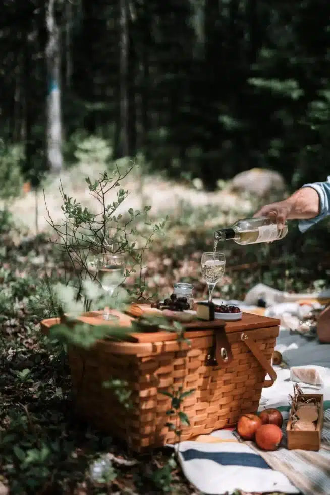 Picknickkorb mit einer Flasche Wein und vielen Leckereien auf einer Decke