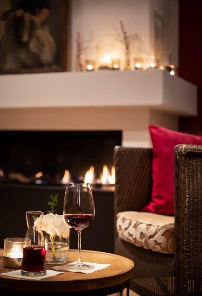 Lounge mit einem Weinglas vor dem Kamin