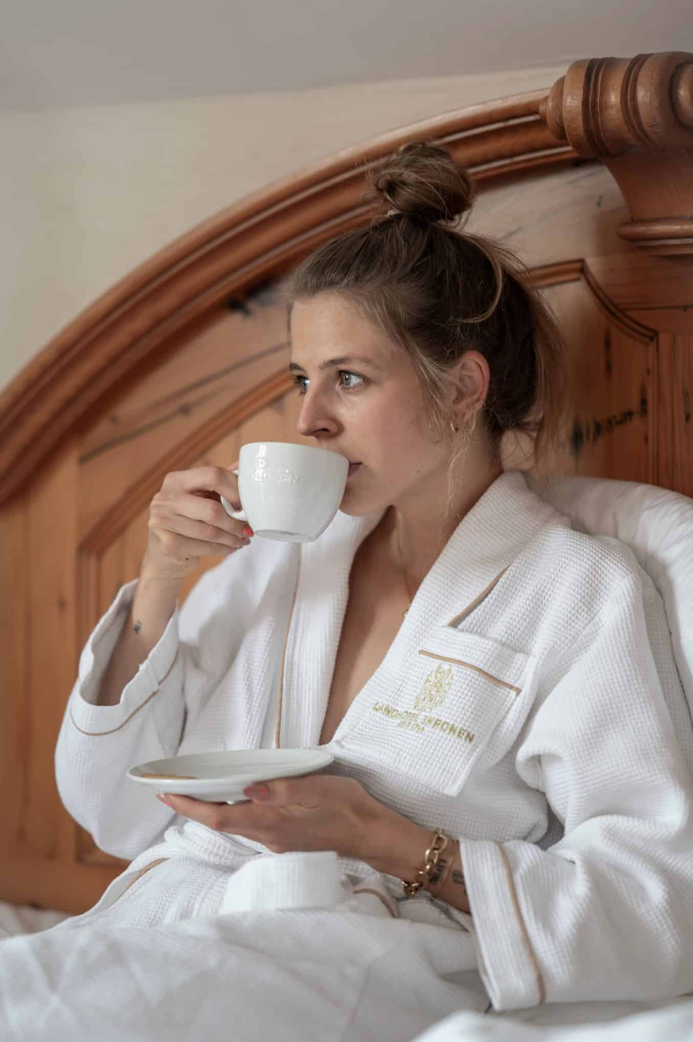 Junge Dame im Bademantel mit Tasse Kaffee im Bett