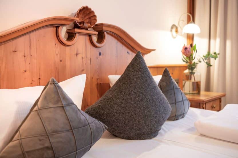 Kopfteil eines Betts im Hotelzimmer mit grauen Kissen