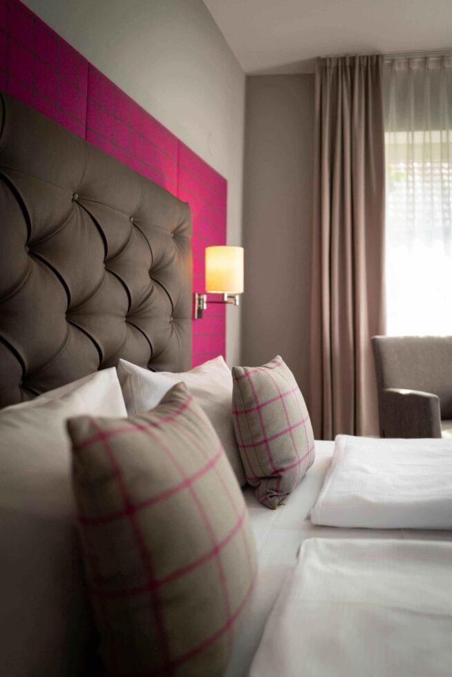 Zimmer mit Kopfteil und pinkem Hintergrund mit Kissen