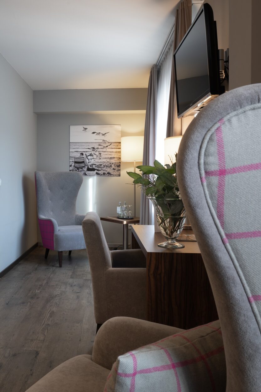 Gemütliche Sitzecke im Hotelzimmer des Landhotel 3Kronen in Adelsdorf mit Ohrensessel, Schreibtisch und warmem Licht