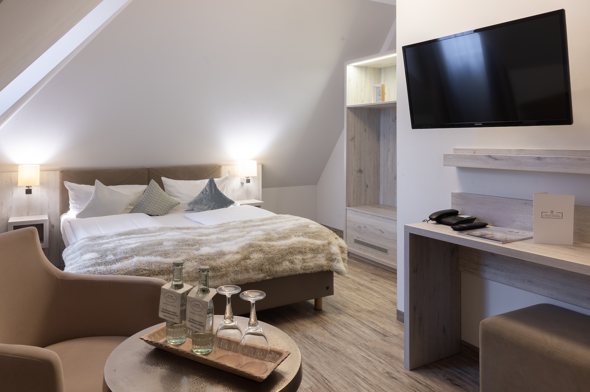 Helles Doppelzimmer im Landhotel 3Kronen mit großem Bett, Dachschräge, Sitzbereich und modernem Holzmobiliar
